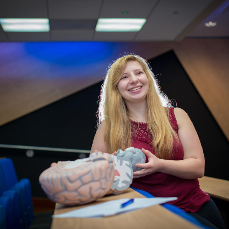 Hull Psychology student, Lisa Stafford, stands smiling holding a model of a brain.