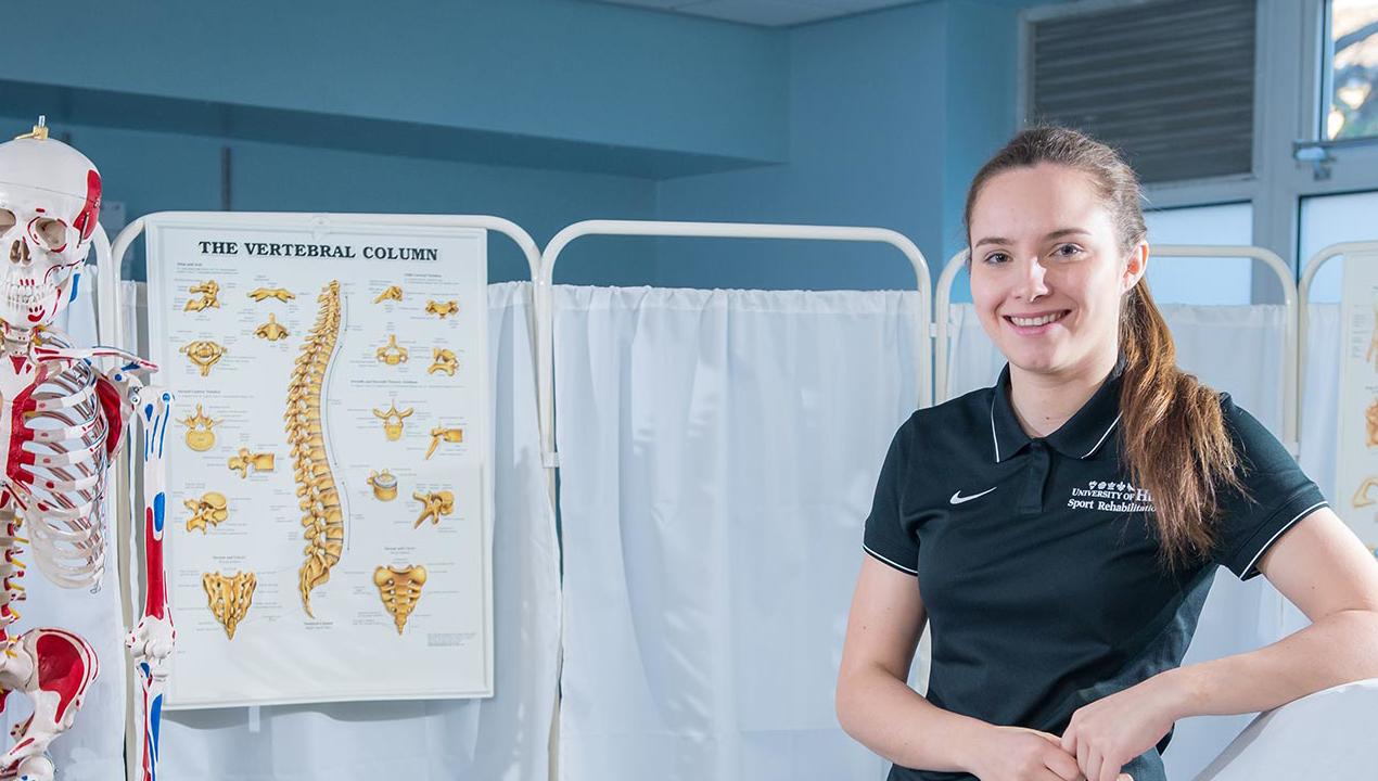 A sport science leans against a raised treatment bed