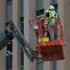 A construction worker in a high vis vest using a cherry picker