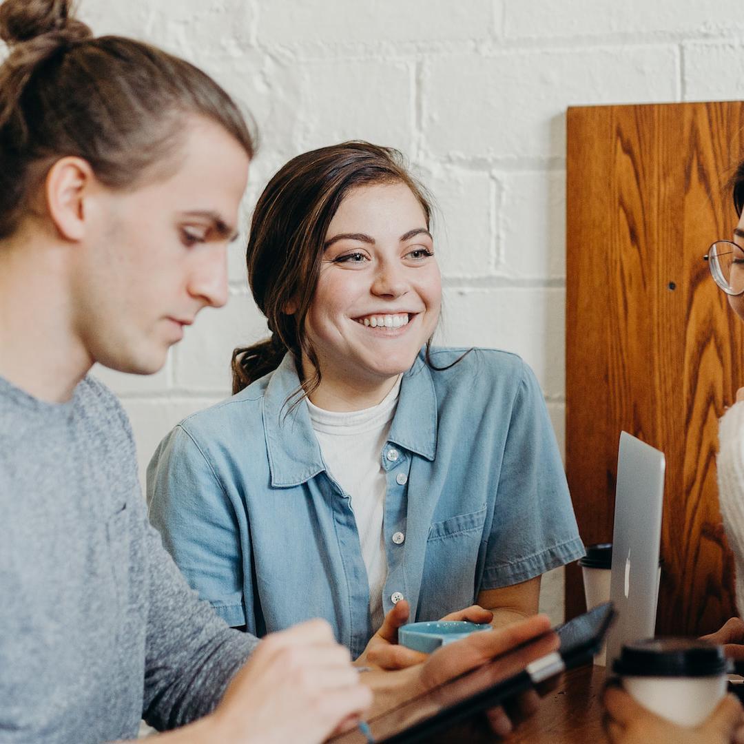 A group of friends chatting over coffee while working on a laptop and tablet 