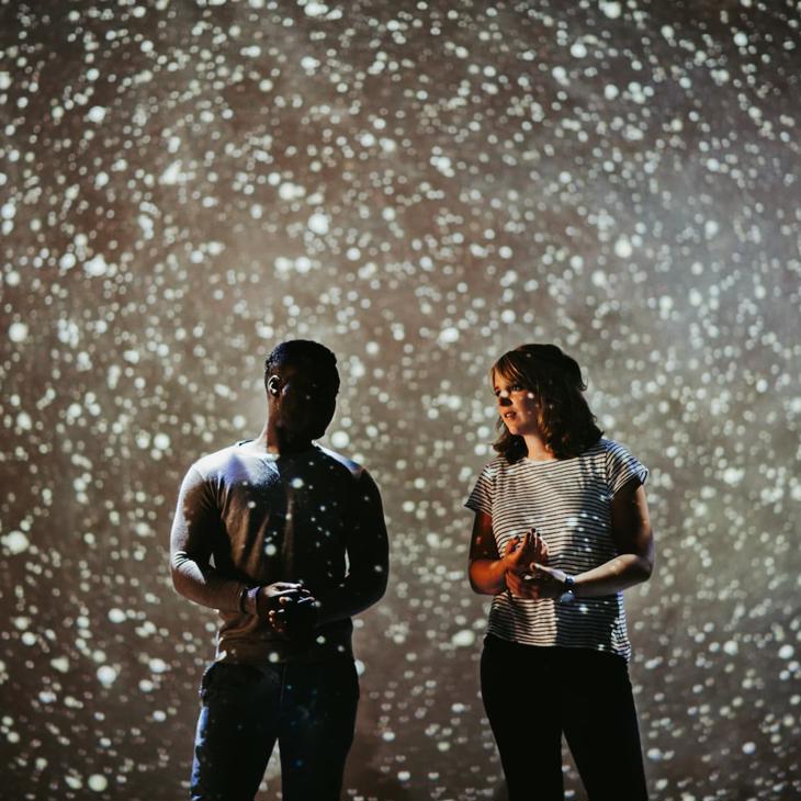 Two students standing on a stage under a starry night