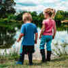 Tw children wearing wellies standing by the side of a lake