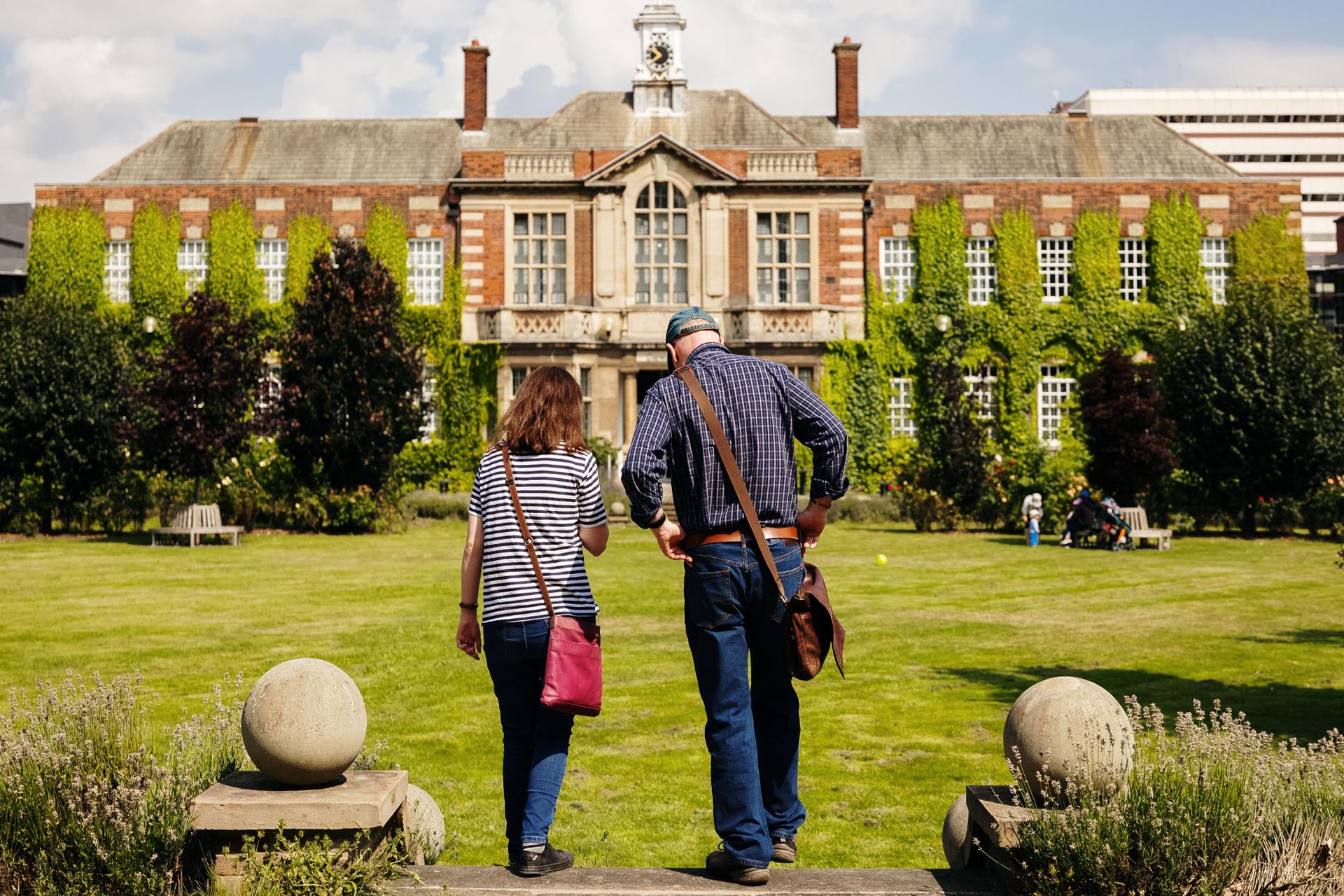Parents walking on grass outside grand University of Hull building.