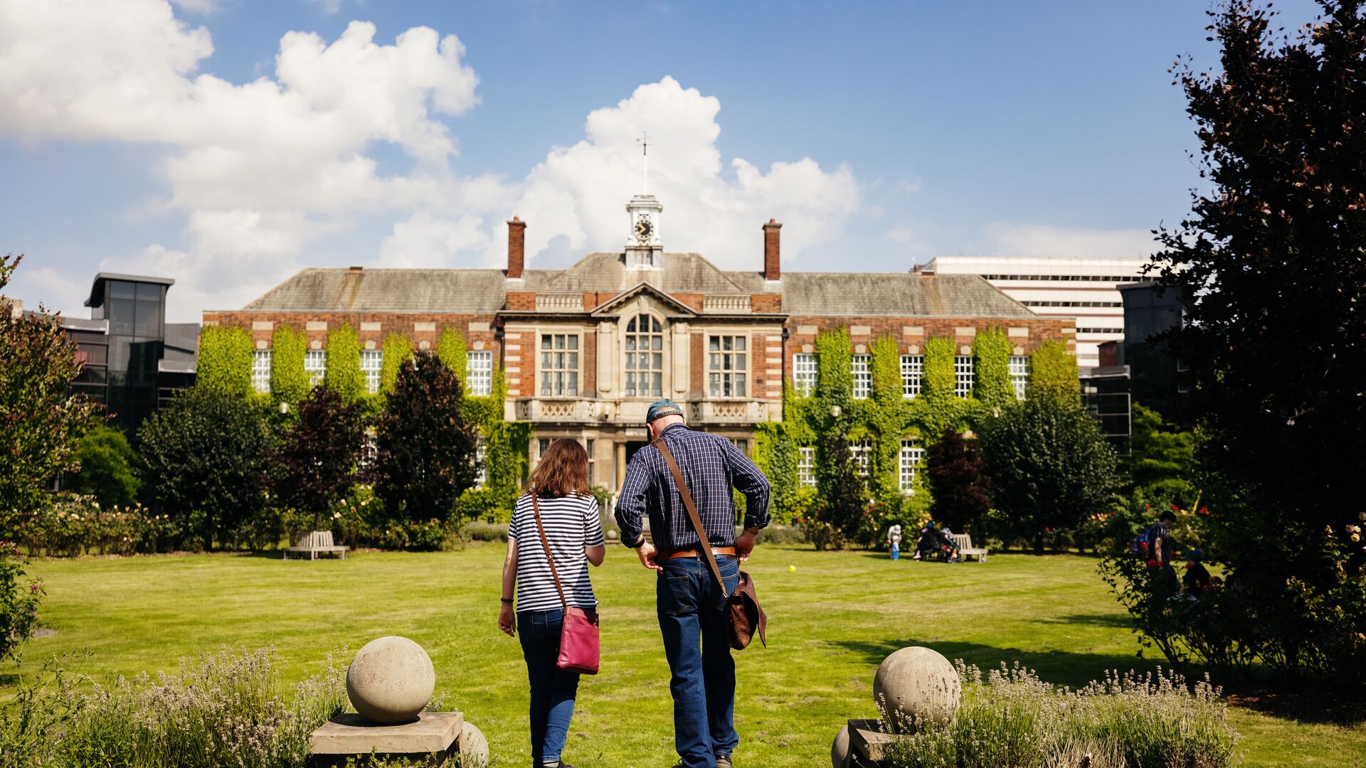 A man and a woman stand with their backs to us at the top of some steps, looking over the University's Rose Bowl.