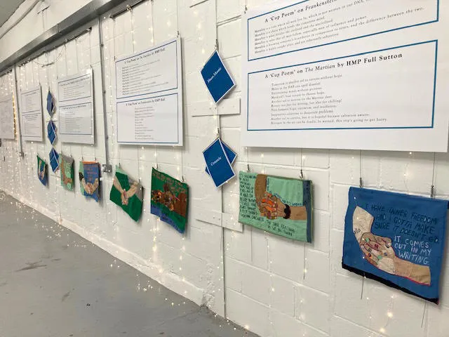 An exhibition wall filled with poetry and textile portrayals of hands with quotes about writing