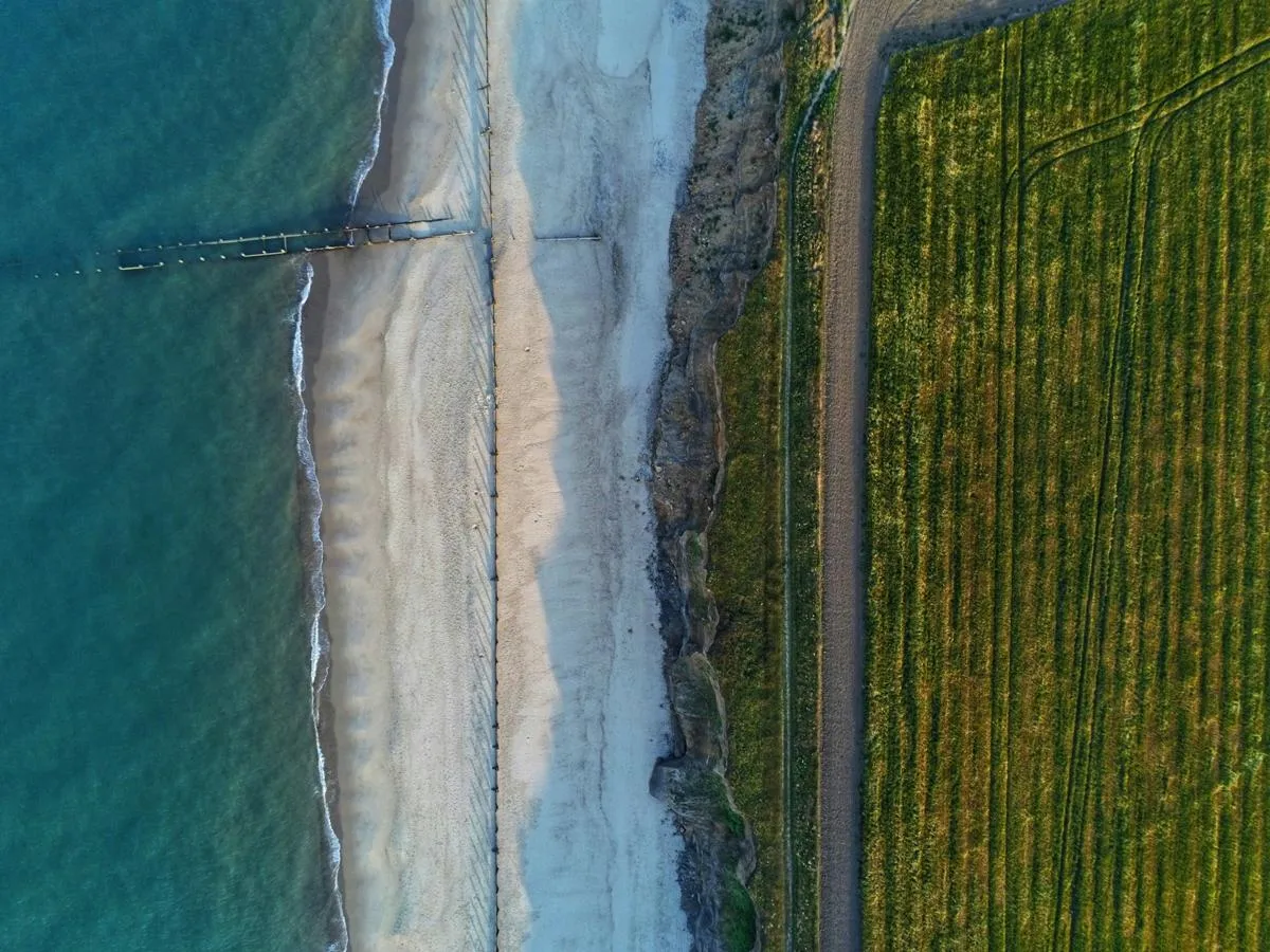 Aerial view of the coast showing blue sea, beach and green land