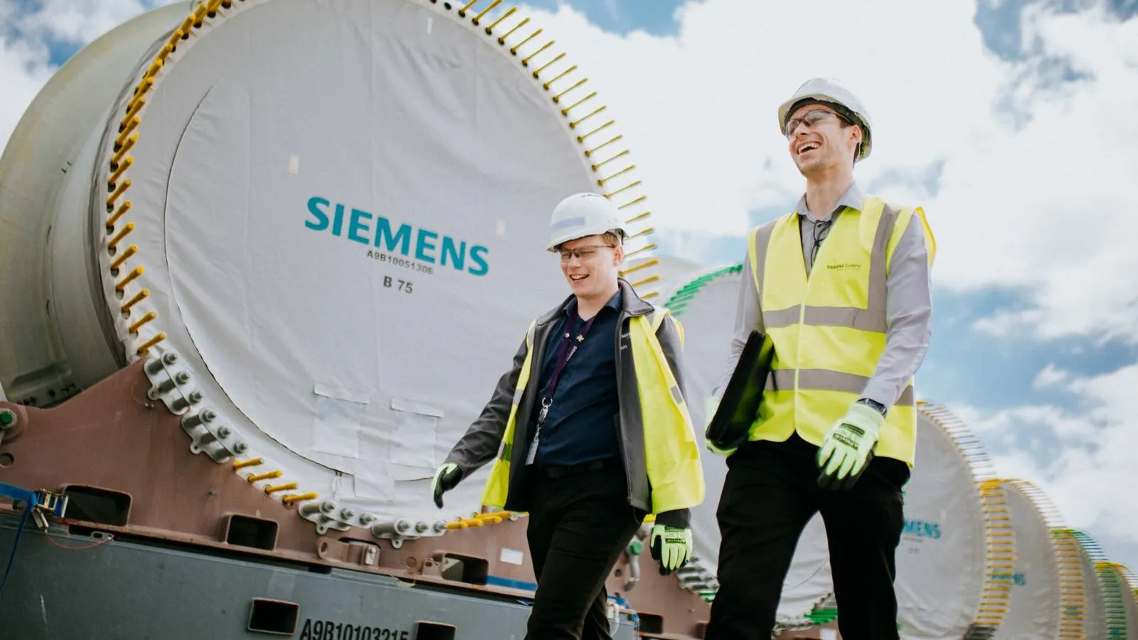 Two employees walk with high-visibility clothing.