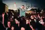 festival crowd with one reveller sat on someone's shoulders enjoying  a band ta night