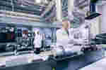 Man in a white coat, gloves and safety glasses works in a lab