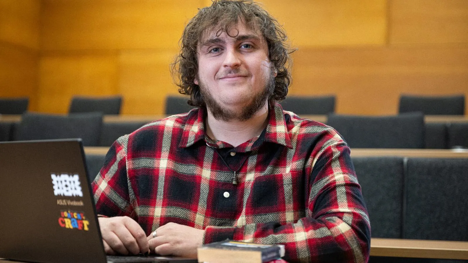 Creative Writing student James Padgett sat at a bench in a lecture theatre with a laptop