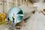 A student in high vis vest stands in front of a turbine blade