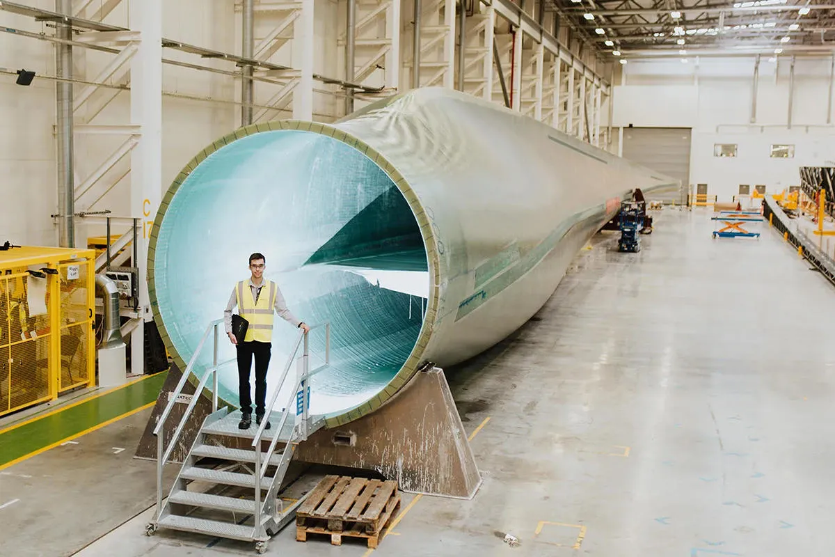 A student in high vis vest stands in front of a turbine blade