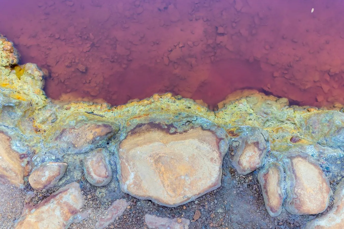 A red river by a stony bank