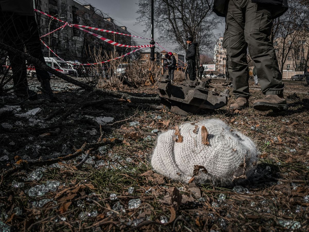 A wooly hat lies on the ground in front of bomb damaged buildings