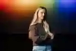 Staff member Lauren stands in front of a wall of prismatic projected colours