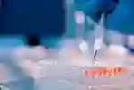 gloved hand pipetting liquid into lab equipment