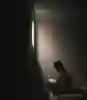 A silhouetted figure sits on a bed reading