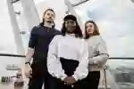 Three students stand together at the tip of The Deep, above the River Humber