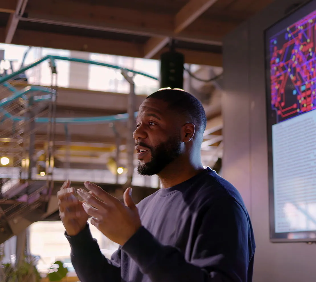 A lecturer teachese in front of a flat screen TV