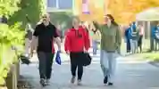 young adult and 2 carers walking through a university campus on a sunny day