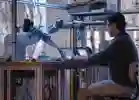 Man working on two laptops controlling robotic arms