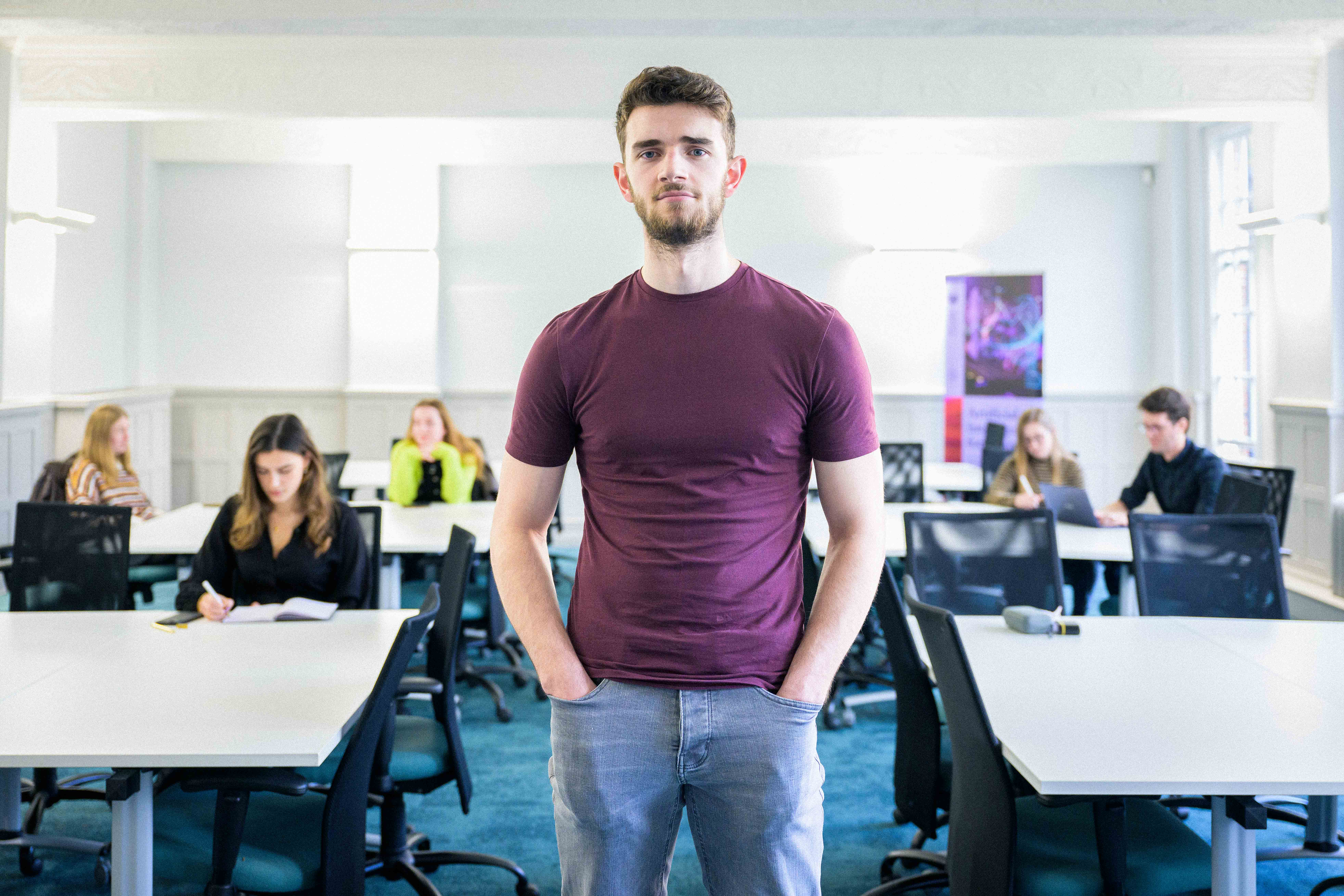 Student stood posing in front of classroom