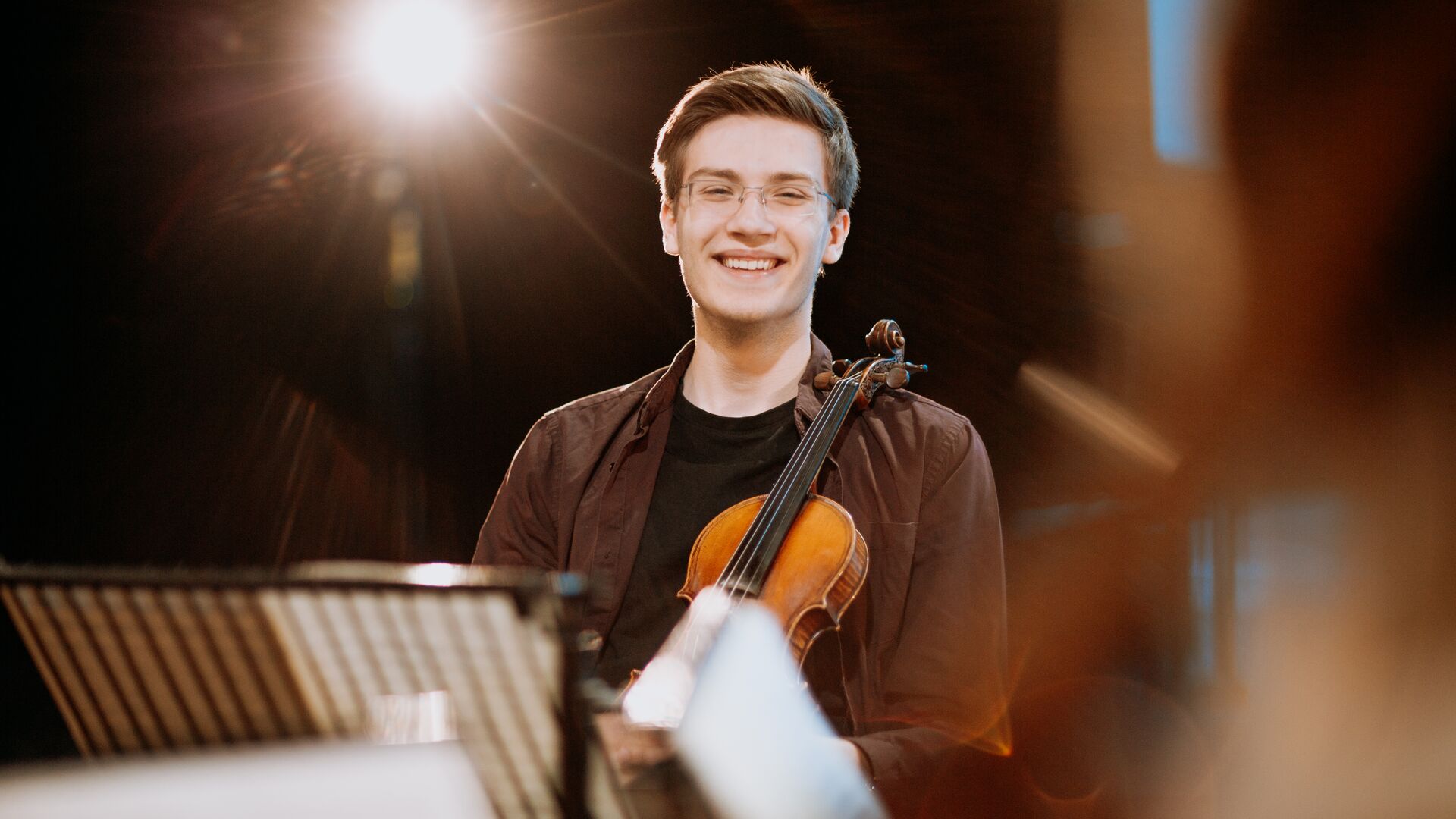 A student holding a violin on stage