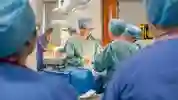 A surgeon in scrubs operates on a patient in a practical session in the operating theatre for students