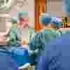 A surgeon in scrubs operates on a patient in a practical session in the operating theatre for students
