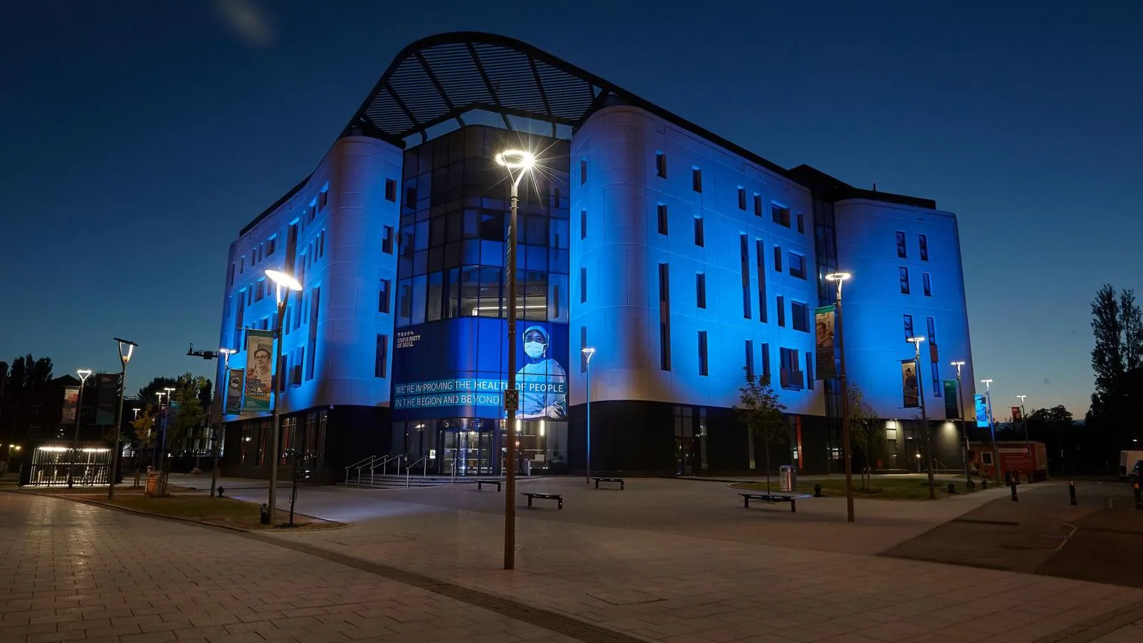 The Allam Medical Building lit with blue spotlights at dusk