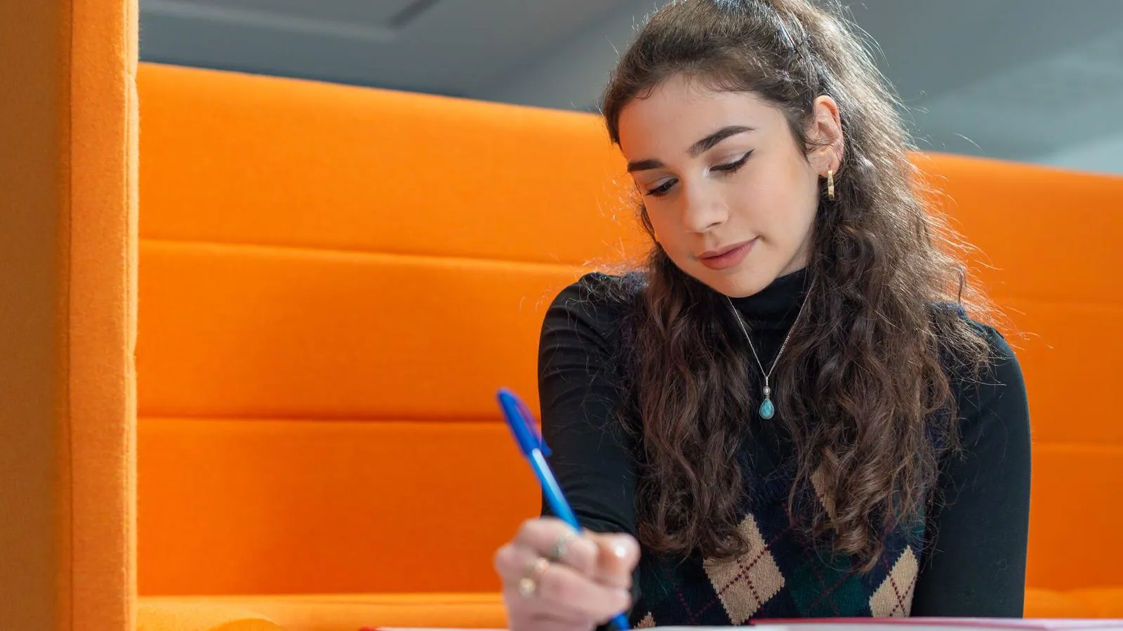 Student sat in a booth writing on paper