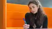 Student sat in a booth writing on paper