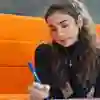 Student sat in a booth writing on paper