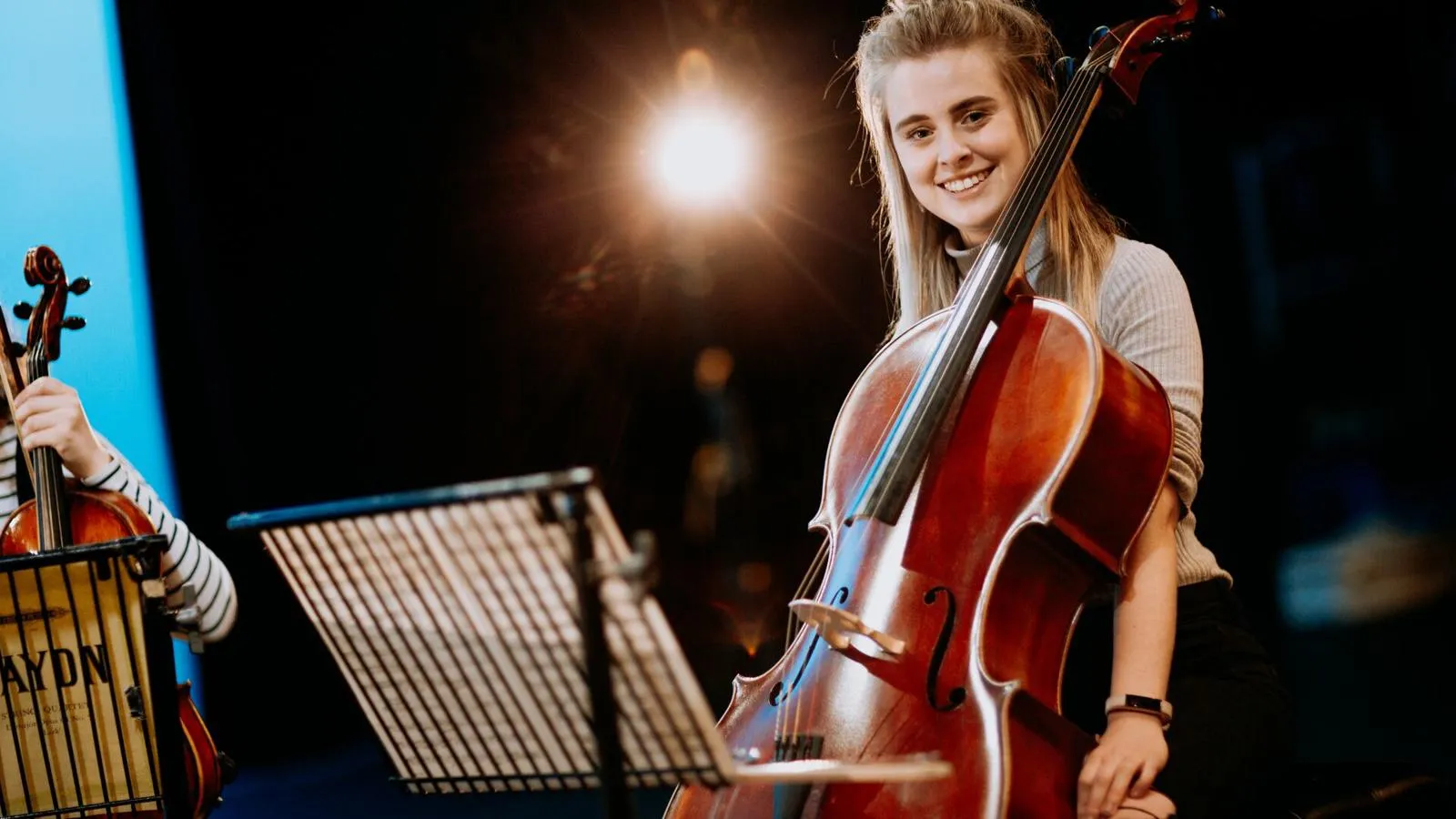 A student with a cello on stage