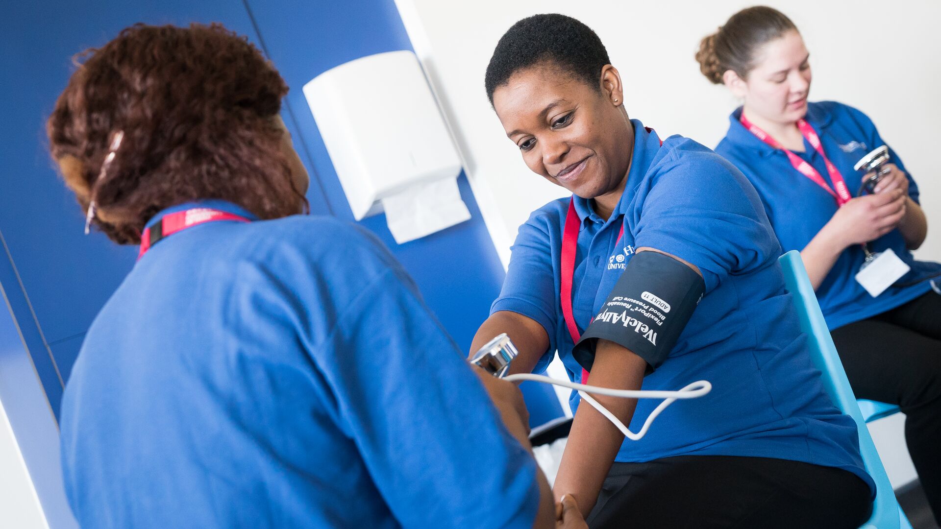 Two health students practise taking each other's blood pressure