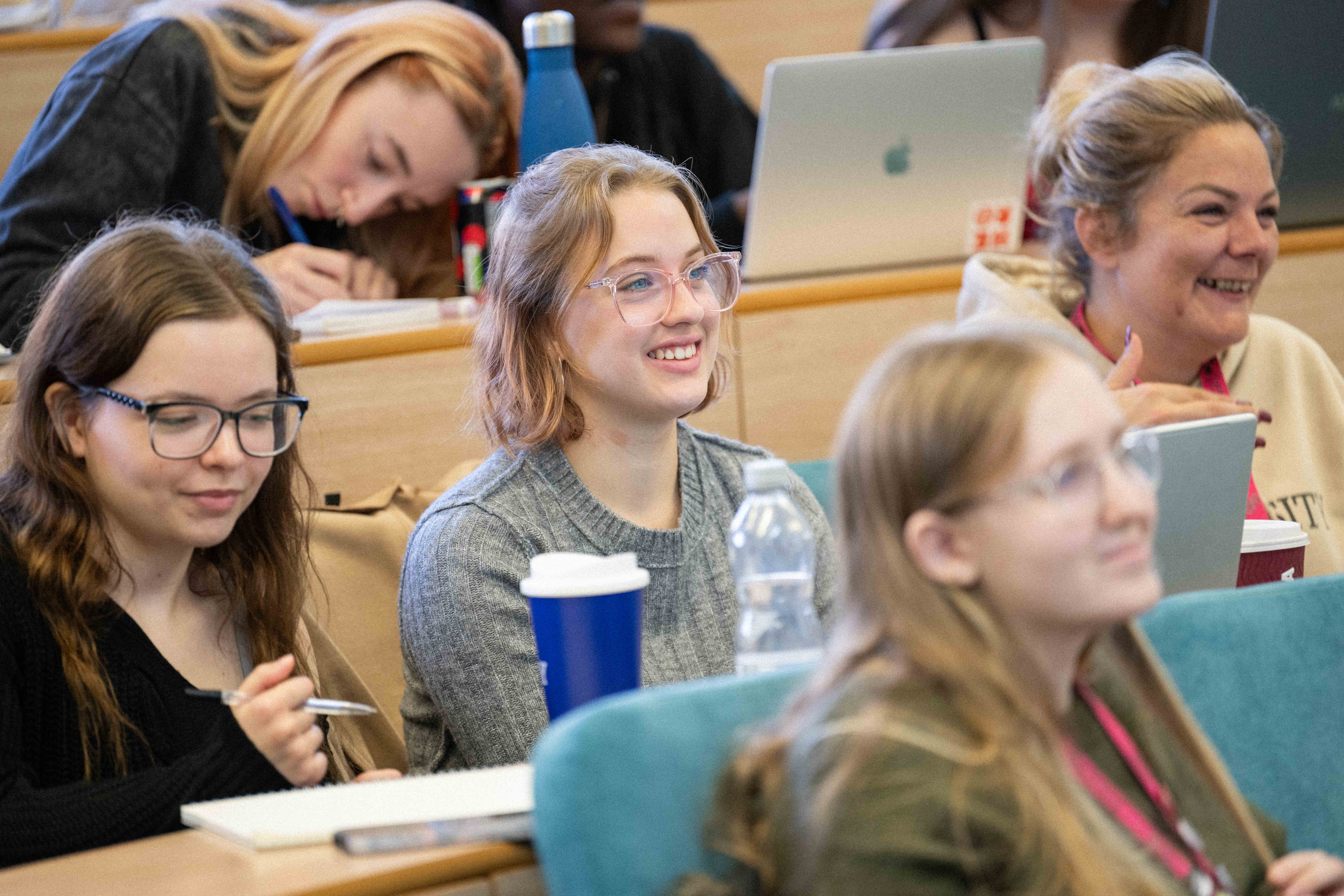 A student sat smiling in a lecture theatre