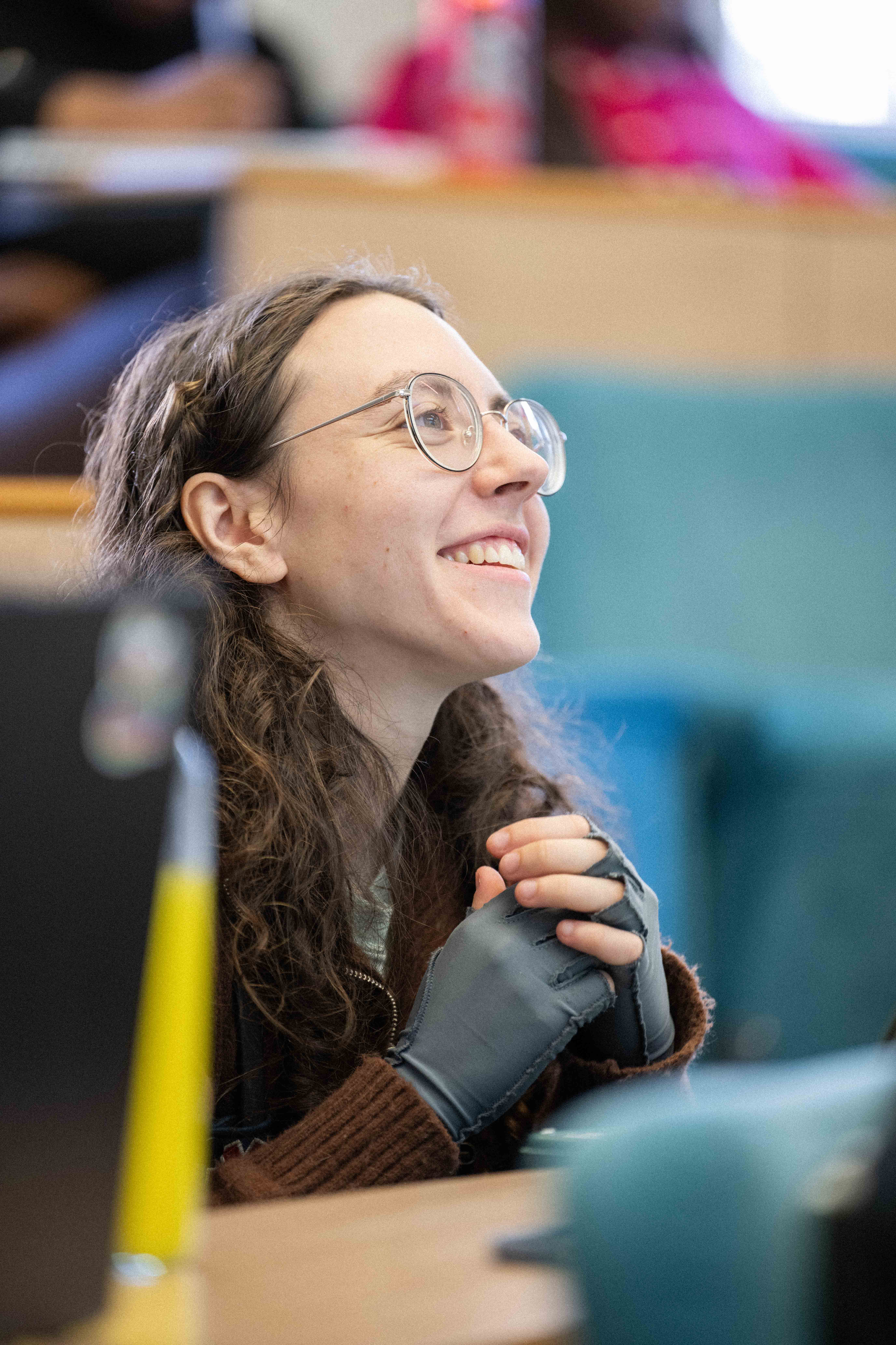 A student smiles whilst watching their lecturer