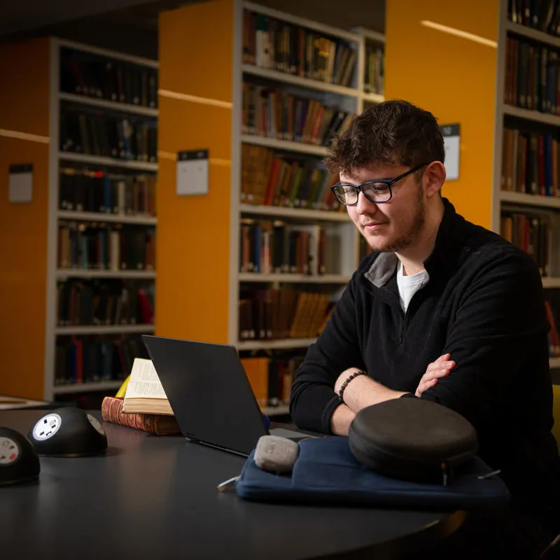Student sat in the library looking at laptop