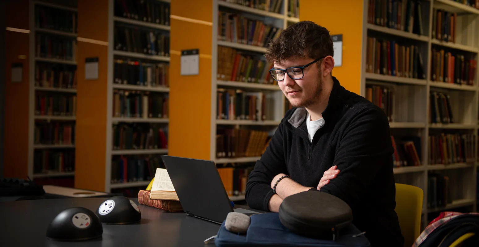 Student sat in the library looking at laptop