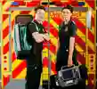 two male and female student paramedics stood in front of mock ambulance