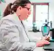 Researcher in white lab coat sat at the computer