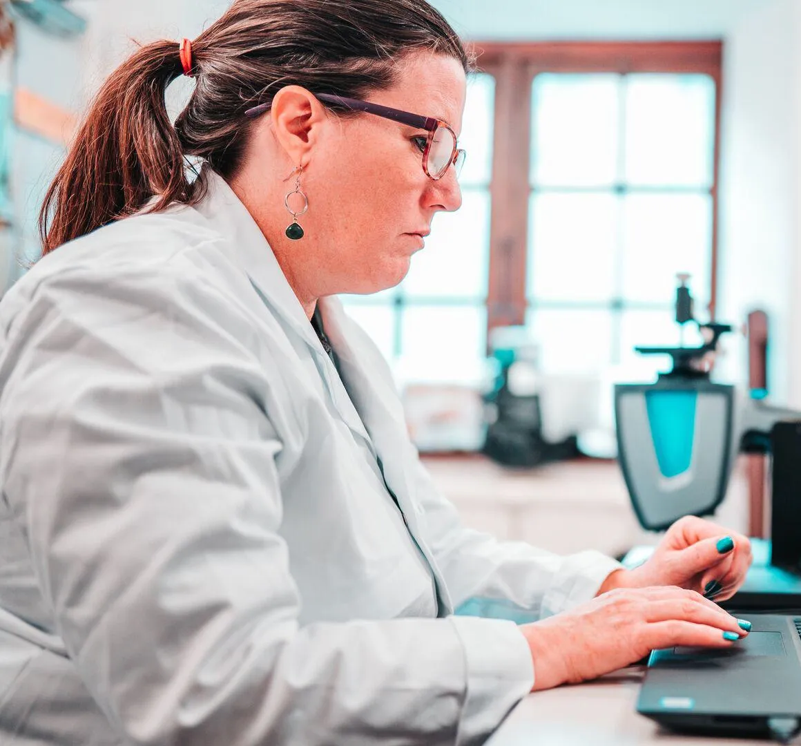 Researcher in white lab coat sat at the computer