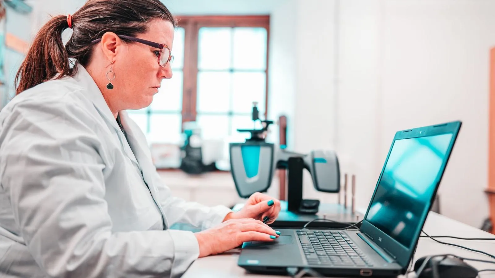 Researcher in white lab coat sat at the computer