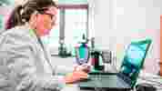 Researcher in white lab coat sat at the computer