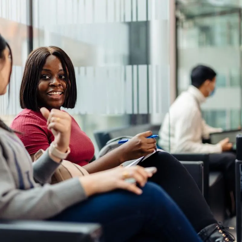 two students on chairs in business lounge chatting