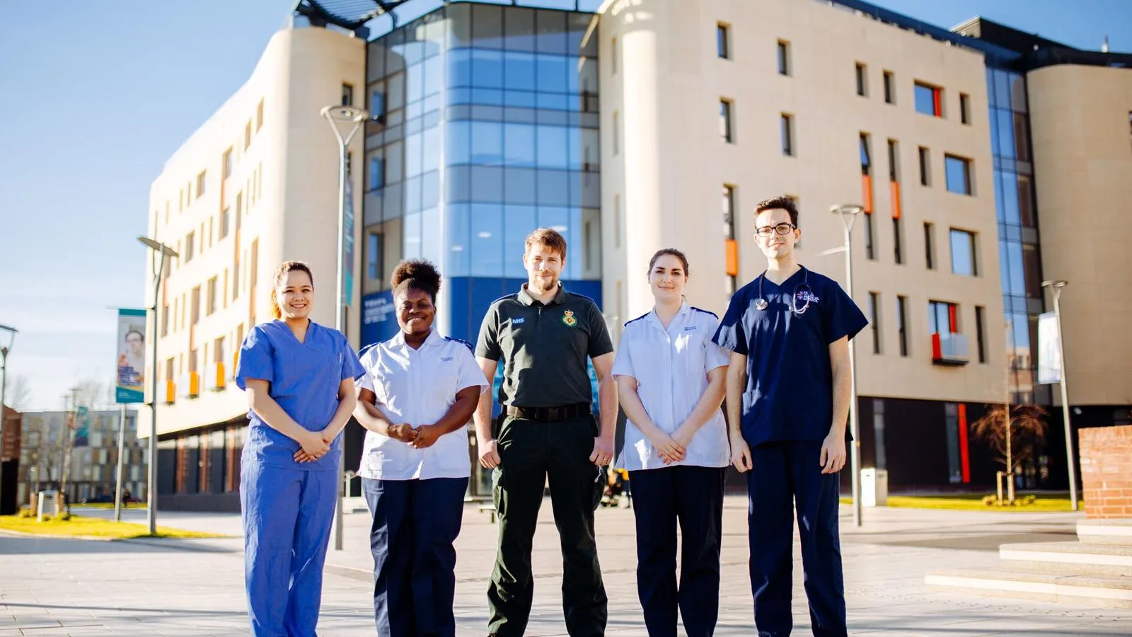 A group of five health students from various fields standing in their respective uniforms