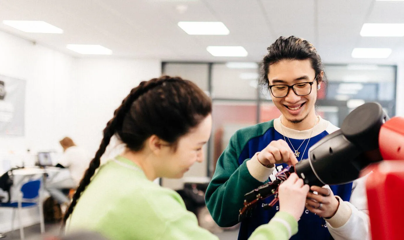 Two students working on a robotic arm