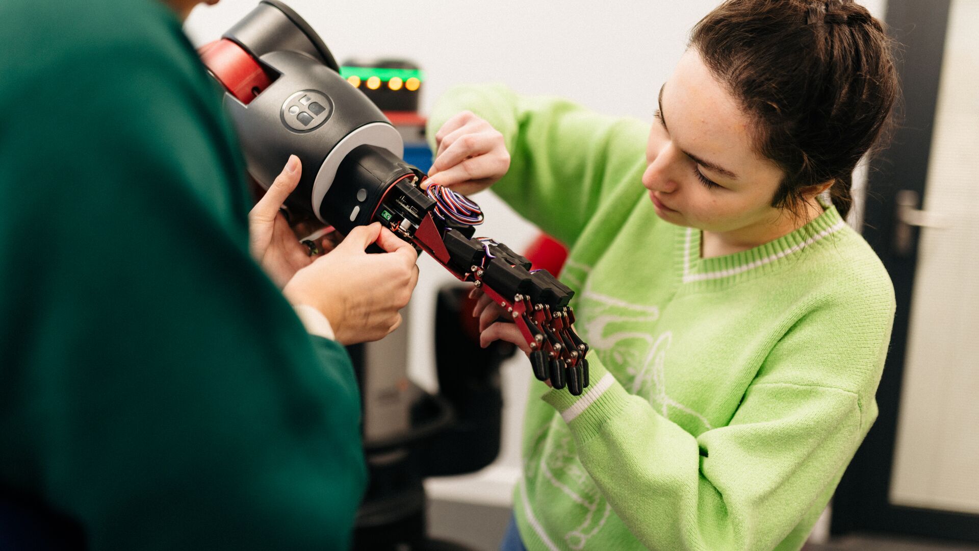 Female student in green jumper working on a robotics hand