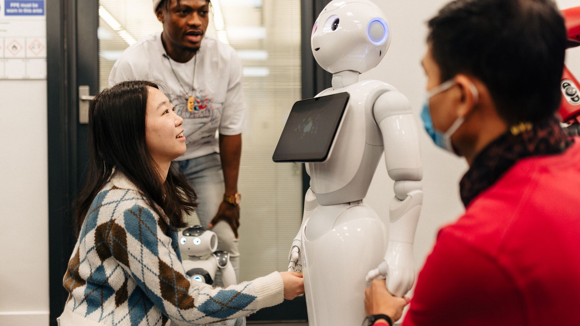 Students examine a robot in the robotics lab