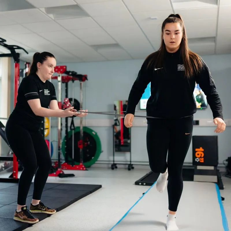 Two students in a rehab suite, one balanced on one leg